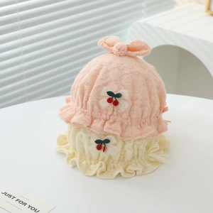 Détail du bonnet en dentelle pour bébé avec applique cerise et nœuds décoratifs doux