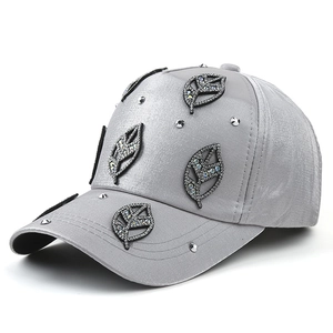 Silver satin baseball cap with rhinestone leaf patches and metallic stud accents