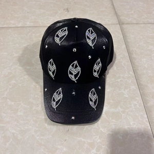 Detailed view of silver rhinestone leaf patterns on a black satin baseball cap