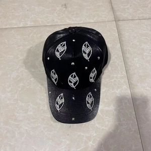 Detail view of black baseball cap with sparkling rhinestone leaf pattern on the shiny crown
