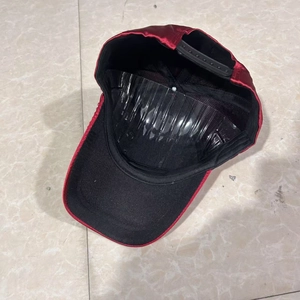 Detailed interior view of red satin baseball cap with black lining and plastic snap closure