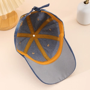Detail view of denim baseball cap interior featuring orange sweatband and metal buckle