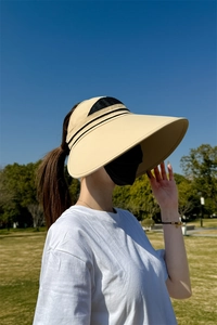 Detailansicht eines beigen Sonnenvisiers mit breiter Krempe und Mesh im Freien