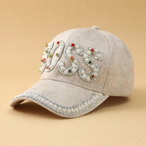 Dettaglio cappellino beige scamosciato con lettere BOSS in perle e strass colorati