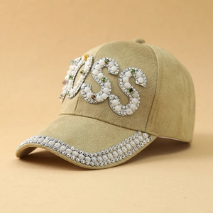 Dettaglio del logo BOSS in perle bianche e strass colorati su berretto in camoscio kaki