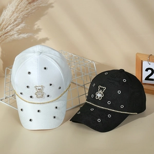 Detail of luxury baseball cap featuring pearl bear pendant and sparkling rhinestone chain
