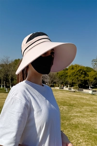 Detail eines rosa Sonnenhuts mit breiter Krempe, schwarzem Netz und UV-Schutz