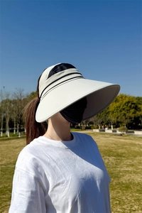 Seitenansicht eines cremefarbenen Sonnenvisiers mit großer Krempe und Mesh-Struktur