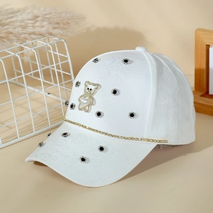 White baseball cap with floral texture featuring a pearl bear charm and rhinestones