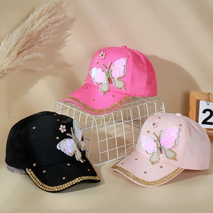 Détail de casquettes pailletées avec papillons, perles et bordure en strass dorés