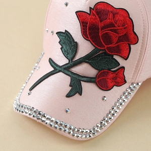 Dettaglio del ricamo floreale e strass brillanti sulla tesa del cappellino rosa