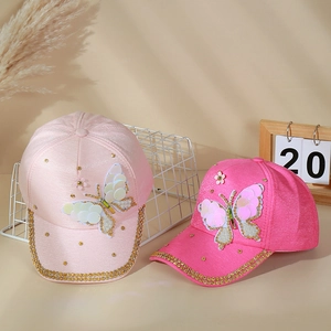 Détail de casquette avec papillon en paillettes, fleurs brodées et strass brillants