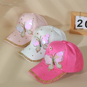 Détail du papillon en paillettes et perles sur une casquette de baseball rose