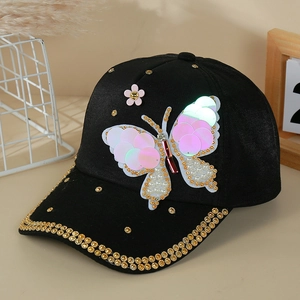 Détail de casquette noire avec papillon en paillettes, perles et strass dorés