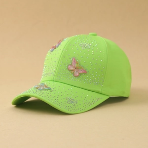 Dettaglio di un cappellino da baseball verde neon con strass bianchi e farfalle 3D colorate