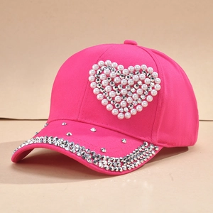 Détail d'une casquette rose avec un motif de cœur en perles et strass brillants