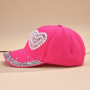 Détail de la casquette rose avec un cœur en perles et une visière ornée de strass