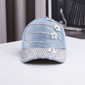 Detailed macro view of white 3D flowers and silver rhinestone stripes on denim baseball cap