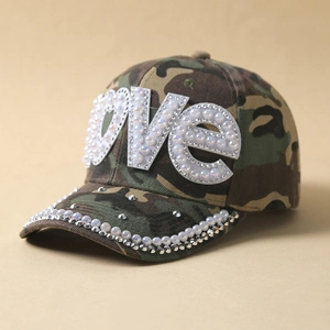 Detail of camouflage baseball cap featuring pearl LOVE lettering and studded brim accents