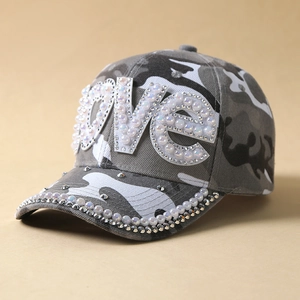 Detail of grey camo baseball cap with LOVE crystal lettering and pearl studs on brim