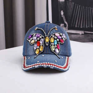 Detailed view of denim baseball cap with large colorful rhinestone butterfly and crystal brim