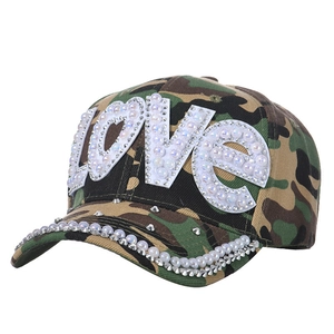 Close-up of camo baseball cap with LOVE patch, pearls, and rhinestones on the brim