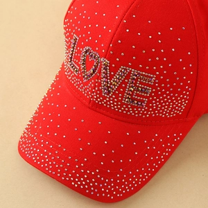 Gros plan détaillé d'une casquette rouge avec lettrage LOVE orné de strass colorés