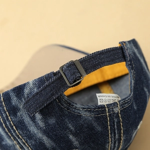 Detail of blue denim baseball cap showing adjustable metal buckle and inner sweatband