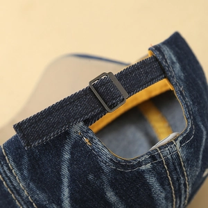 Detail of blue denim baseball cap showing adjustable metal buckle and washed fabric texture