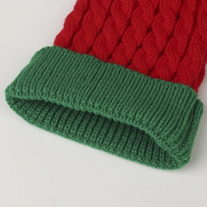 Detail von rotem Zopfmuster und grünem Rippenbündchen an festlicher Kinder-Strickmütze