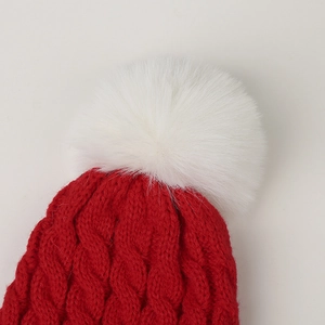 Detailaufnahme der roten Zopfstrickmütze mit großem weißem Kunstfell-Pompon für Winter