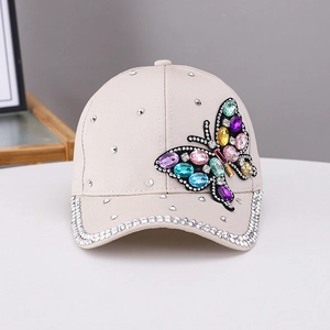 Dettaglio farfalla in strass colorati su un cappellino da baseball in cotone beige