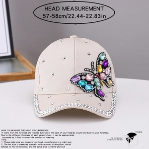 Dettaglio del cappello beige con farfalla di strass colorati e guida alle taglie indicata