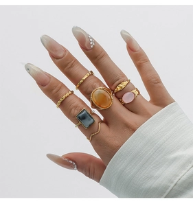 Close-up of a 7-piece set of gold-toned alloy rings with colorful resin stones on hand