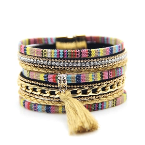 Detail of bohemian multilayer bracelet with colorful fabric, gold chains, and fringe