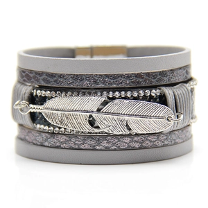 Close-up of bohemian grey leather multi-layer bracelet with silver feather and rhinestones