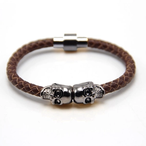 Close-up of brown braided leather bracelet with silver skull charms and magnetic clasp