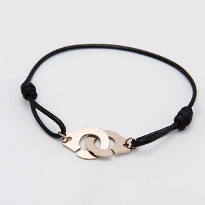Minimalist black braided bracelet featuring interlocking rose gold handcuff charms
