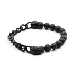 Detail of black lava stone beads and metal skull charm on a punk style men's bracelet
