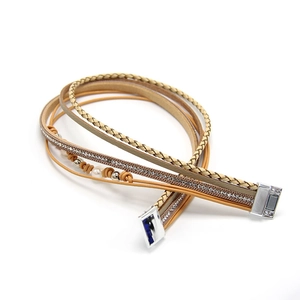 Détail d'un bracelet multicouche avec fermoir magnétique, cordons tressés et strass