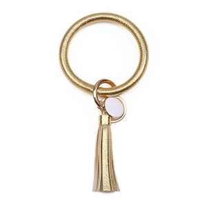 Detail shot of golden PU leather bracelet keychain with tassel and round metal tag