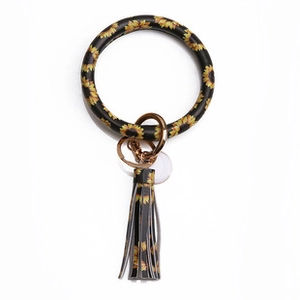 Detail of round sunflower print keychain charm with matching black and yellow leather tassel