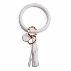 Détail d'un porte-clés en similicuir blanc à motif serpent avec pompon et fermoir doré