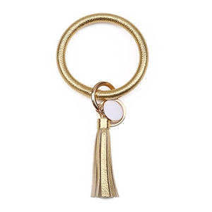 Macro detail of golden PU leather keychain ring with stylish fringe tassel and round tag