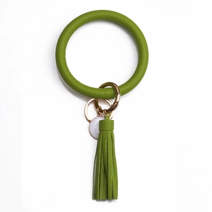 Détail d'un porte-clés en similicuir vert herbe avec gland et fermoir doré sur fond blanc