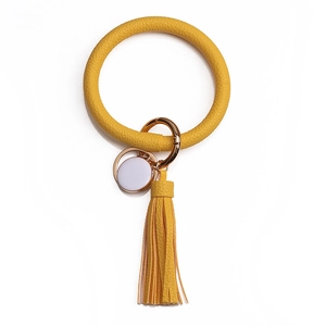 Détail du bracelet porte-clés en cuir PU jaune avec pompon et accessoires en métal doré