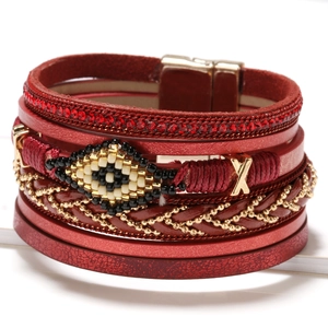 Macro detail of red layered leather bracelet with handmade evil eye beadwork and red crystals