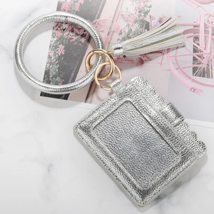 Silver faux leather wristlet keychain with card holder and tassel on marble surface