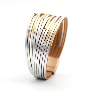 Detail eines mehrlagigen Lederarmbands mit roségoldenem Magnetverschluss und Metallrohren