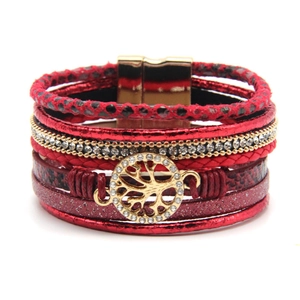 Detailaufnahme des roten Wickelarmbands mit goldenem Lebensbaum-Anhänger und Strasssteinen
